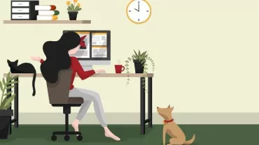 Woman working at a desk with plants, cat on desk, dog on floor.