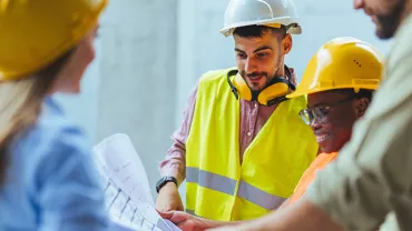 Construction team reviewing blueprints on site.