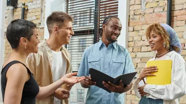 Diverse group of four people having a discussion in a bright office.