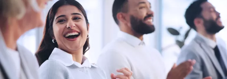 Group of people smiling and clapping in a bright room.