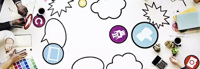 Creative team brainstorming around a table with colorful icons and sketches.