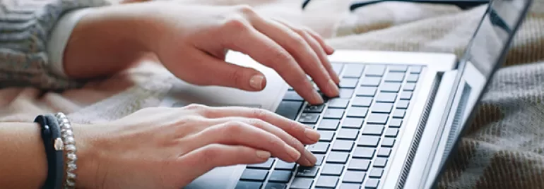 Hands typing on a laptop keyboard.